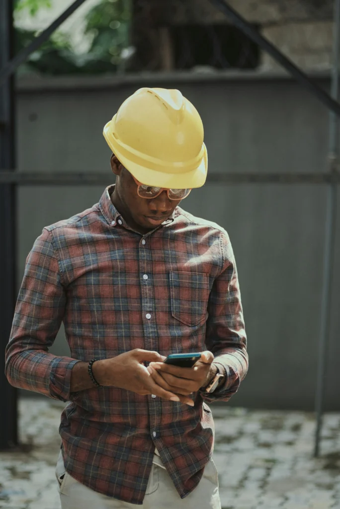 Tradesman in a hard hat searching on his smartphone